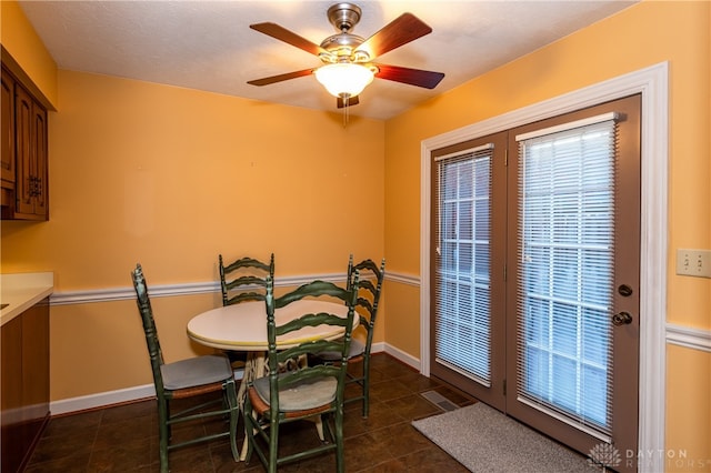 dining area with a textured ceiling, ceiling fan, and dark tile patterned flooring