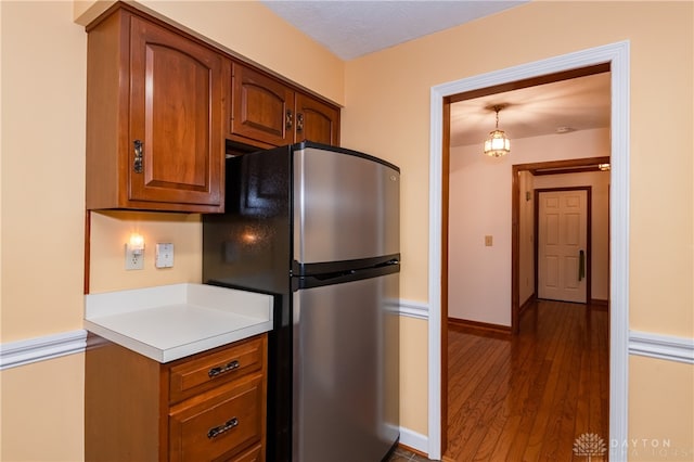 kitchen featuring stainless steel fridge, a textured ceiling, dark hardwood / wood-style floors, and pendant lighting