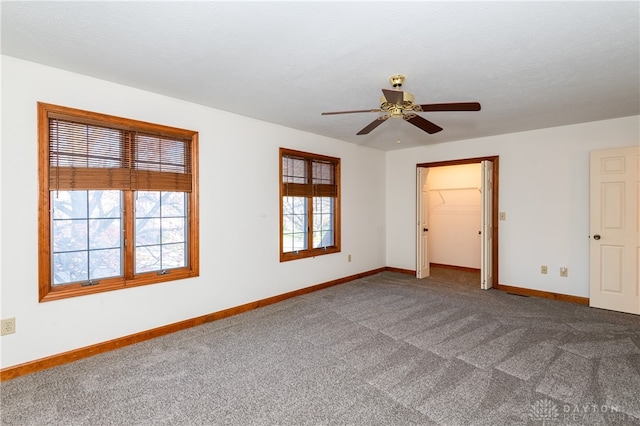 unfurnished bedroom with ceiling fan, a walk in closet, carpet floors, and a closet