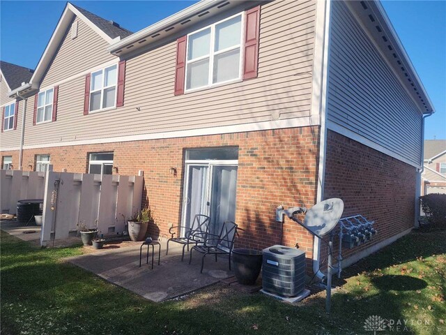 rear view of house featuring a yard, central AC unit, and a patio area