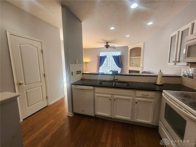 kitchen with white appliances, dark hardwood / wood-style flooring, kitchen peninsula, and sink