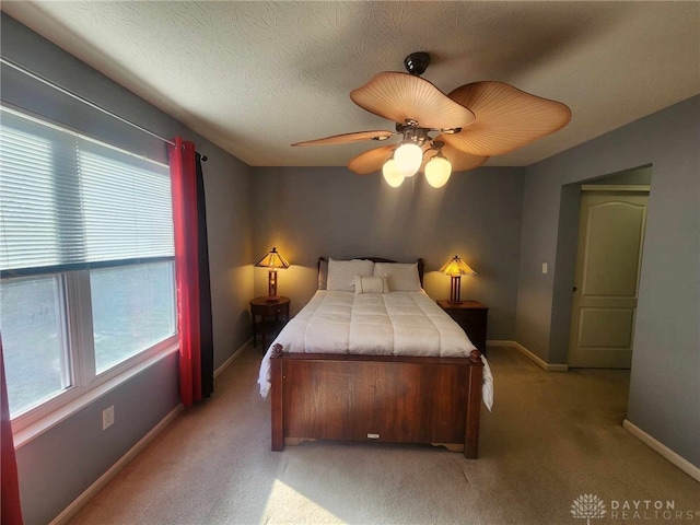 carpeted bedroom with ceiling fan and a textured ceiling