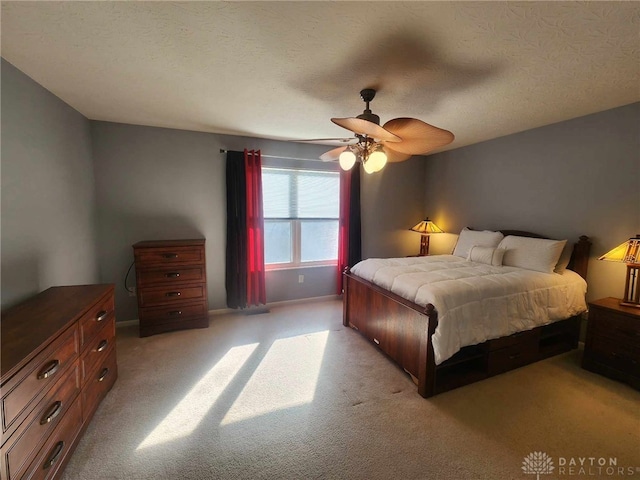 carpeted bedroom featuring ceiling fan and a textured ceiling