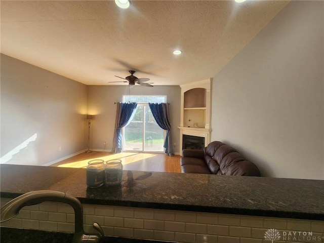 living room with wood-type flooring, ceiling fan, and a textured ceiling