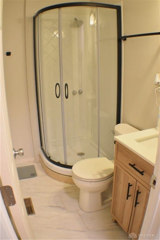 bathroom with vanity, an enclosed shower, and toilet