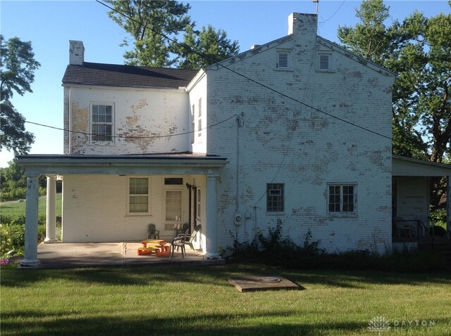 back of property featuring a patio area and a lawn