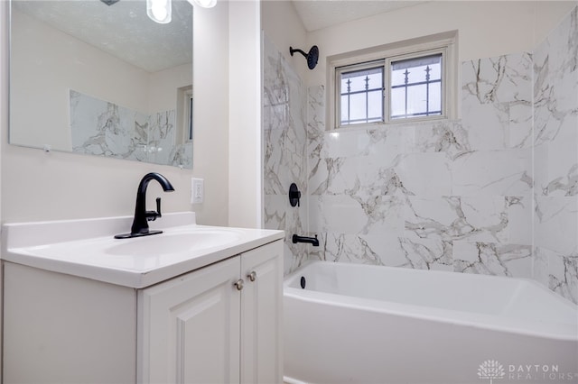 bathroom with vanity, a textured ceiling, and tiled shower / bath