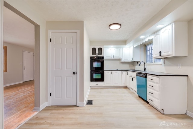 kitchen featuring white cabinetry, sink, stainless steel dishwasher, double oven, and a textured ceiling