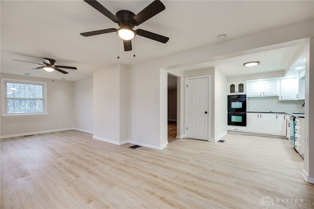 unfurnished living room featuring ceiling fan, a textured ceiling, and light hardwood / wood-style flooring