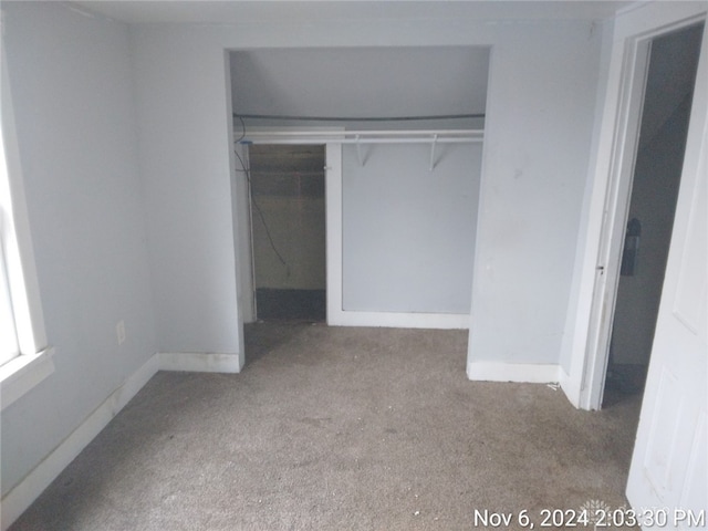 unfurnished bedroom featuring light carpet and a closet