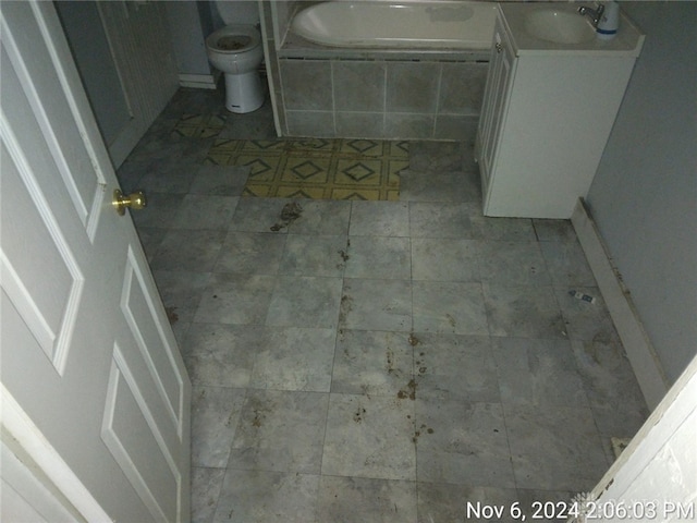 bathroom with tiled bath, sink, tile patterned flooring, and toilet