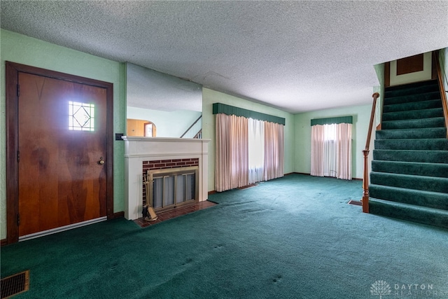 unfurnished living room with dark colored carpet, a textured ceiling, and a brick fireplace