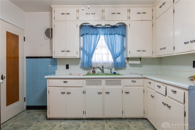 kitchen with sink, white cabinets, and tile walls