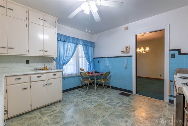 kitchen with ceiling fan with notable chandelier, white electric range, hanging light fixtures, tile walls, and white cabinetry