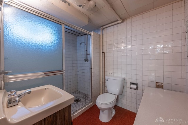 bathroom with sink, a shower with shower door, tile walls, and toilet