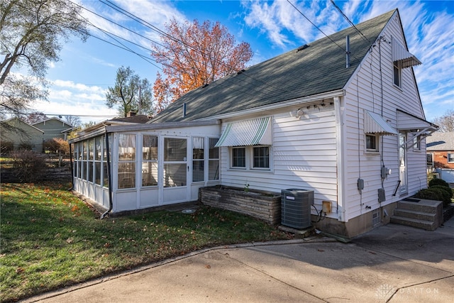 rear view of house featuring cooling unit, a lawn, and a sunroom