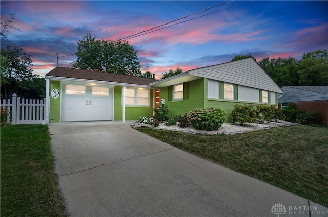 ranch-style home featuring a lawn and a garage