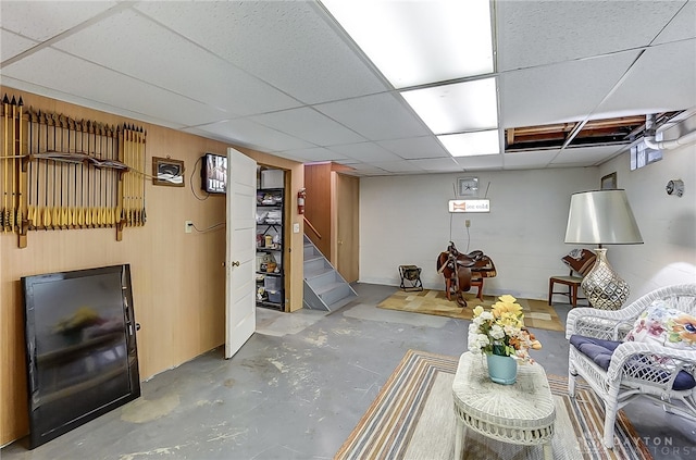 living room with a paneled ceiling and concrete floors