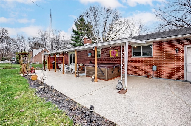 rear view of house featuring a hot tub and a patio area