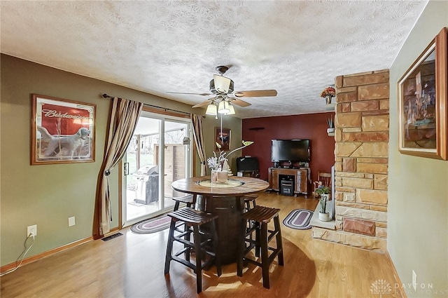 dining room featuring a textured ceiling, light hardwood / wood-style flooring, and ceiling fan