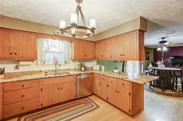 kitchen with a textured ceiling, sink, dishwasher, light hardwood / wood-style floors, and hanging light fixtures