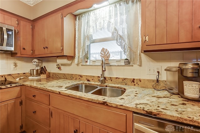 kitchen featuring backsplash, light stone countertops, sink, and appliances with stainless steel finishes