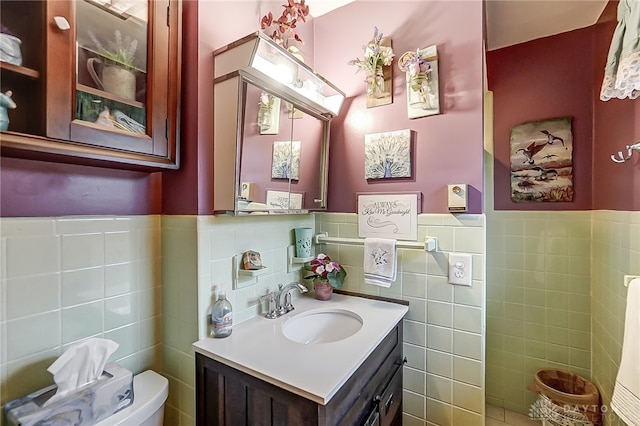 bathroom featuring vanity, tile walls, and toilet