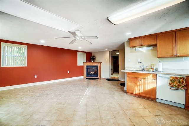 kitchen featuring a fireplace, ceiling fan, sink, light tile patterned floors, and dishwasher