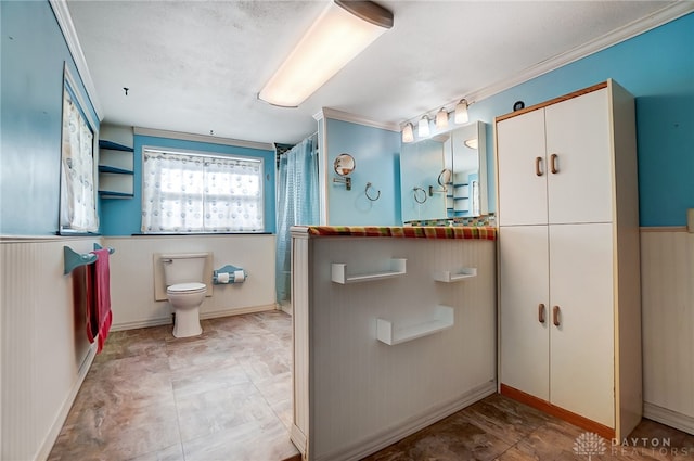 bathroom featuring toilet, crown molding, and wood walls