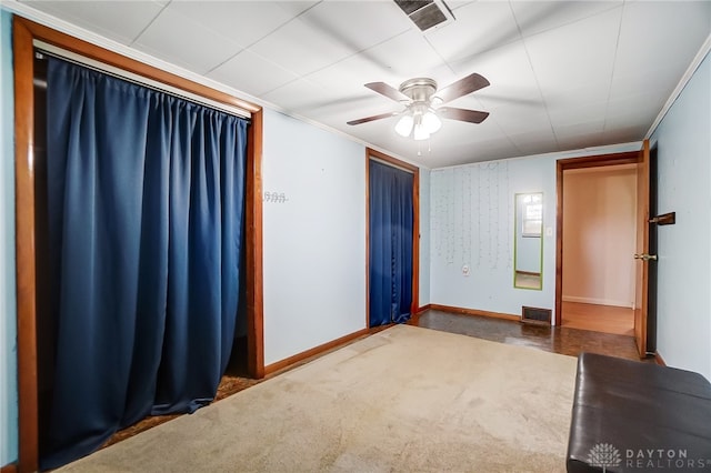 empty room featuring dark carpet, ceiling fan, and crown molding