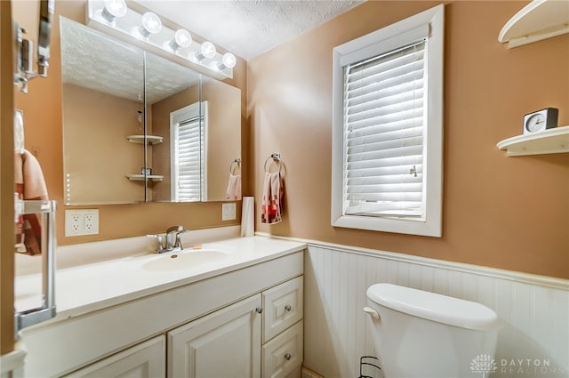 bathroom featuring vanity, a healthy amount of sunlight, toilet, and a textured ceiling