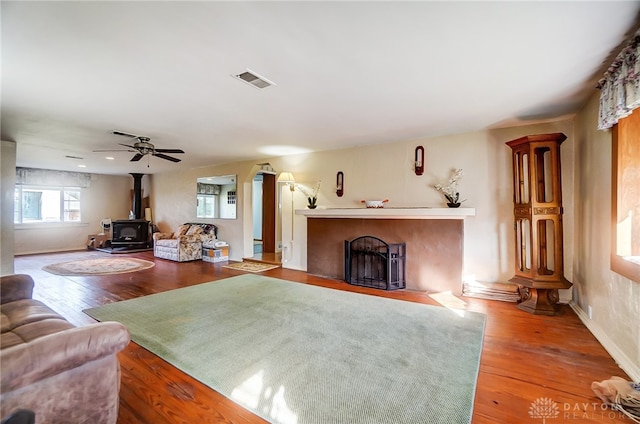 living room featuring a wood stove, ceiling fan, and hardwood / wood-style floors