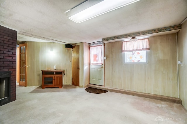 basement featuring carpet floors, a textured ceiling, and a brick fireplace