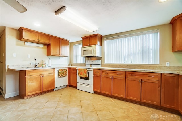 kitchen featuring sink, light tile patterned flooring, and white appliances