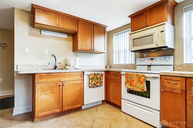 kitchen with plenty of natural light, light tile patterned flooring, white appliances, and sink