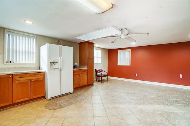 kitchen featuring ceiling fan, white refrigerator with ice dispenser, and light tile patterned floors