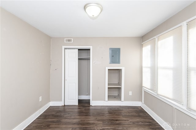 unfurnished bedroom featuring dark hardwood / wood-style flooring, electric panel, and a closet