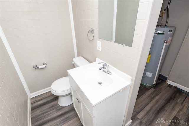 bathroom featuring hardwood / wood-style floors, vanity, tile walls, and water heater