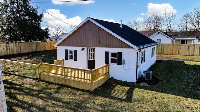 rear view of house featuring a wooden deck, cooling unit, and a lawn