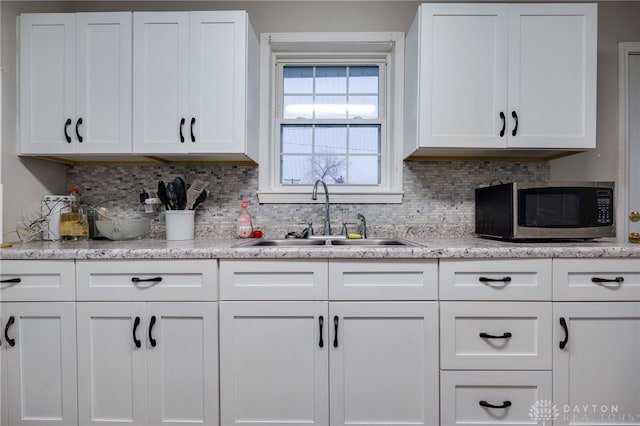 kitchen with decorative backsplash, white cabinetry, and sink