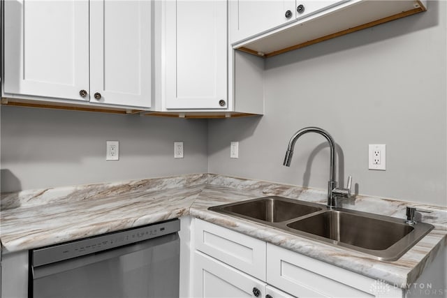 kitchen featuring light stone counters, white cabinetry, stainless steel dishwasher, and sink