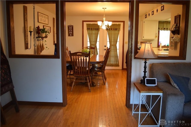 dining space with french doors, light hardwood / wood-style floors, and a notable chandelier