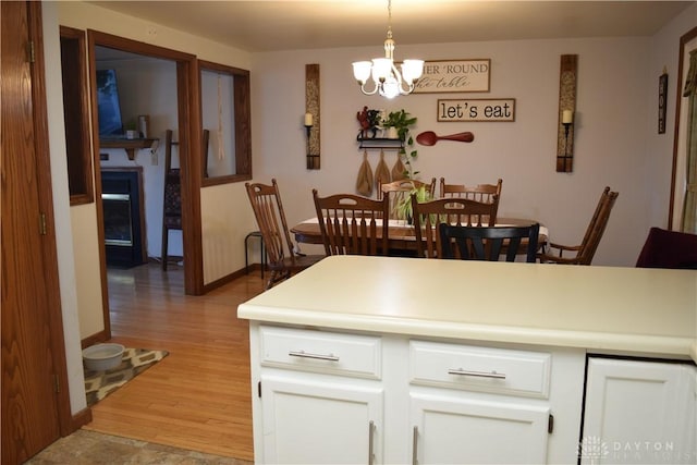 interior space featuring white cabinets, an inviting chandelier, decorative light fixtures, and light hardwood / wood-style flooring