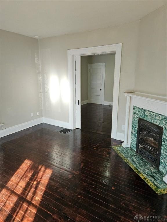 unfurnished living room with dark hardwood / wood-style flooring and a high end fireplace