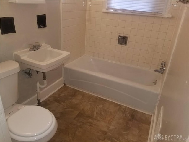 full bathroom featuring tiled shower / bath combo, toilet, and sink