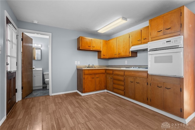 kitchen with sink, stovetop, oven, and light wood-type flooring