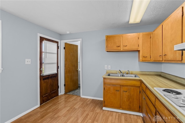 kitchen featuring a textured ceiling, white stovetop, sink, and light hardwood / wood-style flooring