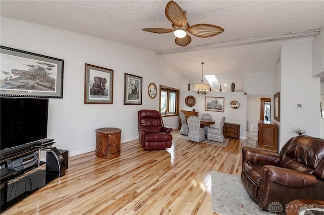 living room featuring a textured ceiling, ceiling fan, light hardwood / wood-style floors, and lofted ceiling