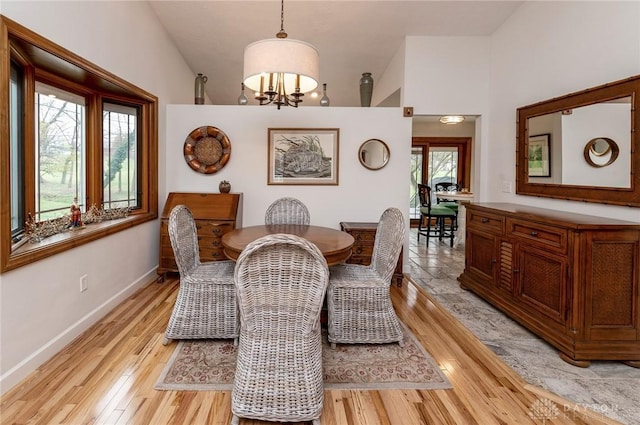 dining area featuring light wood-type flooring, vaulted ceiling, and a notable chandelier