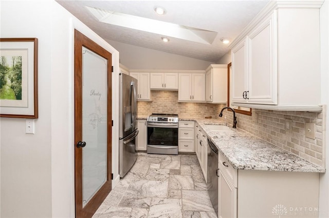 kitchen with light stone countertops, decorative backsplash, stainless steel appliances, sink, and lofted ceiling